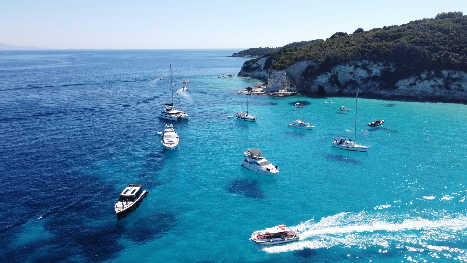 Boats anchored in a turquoise cove off Paxos, Greece
