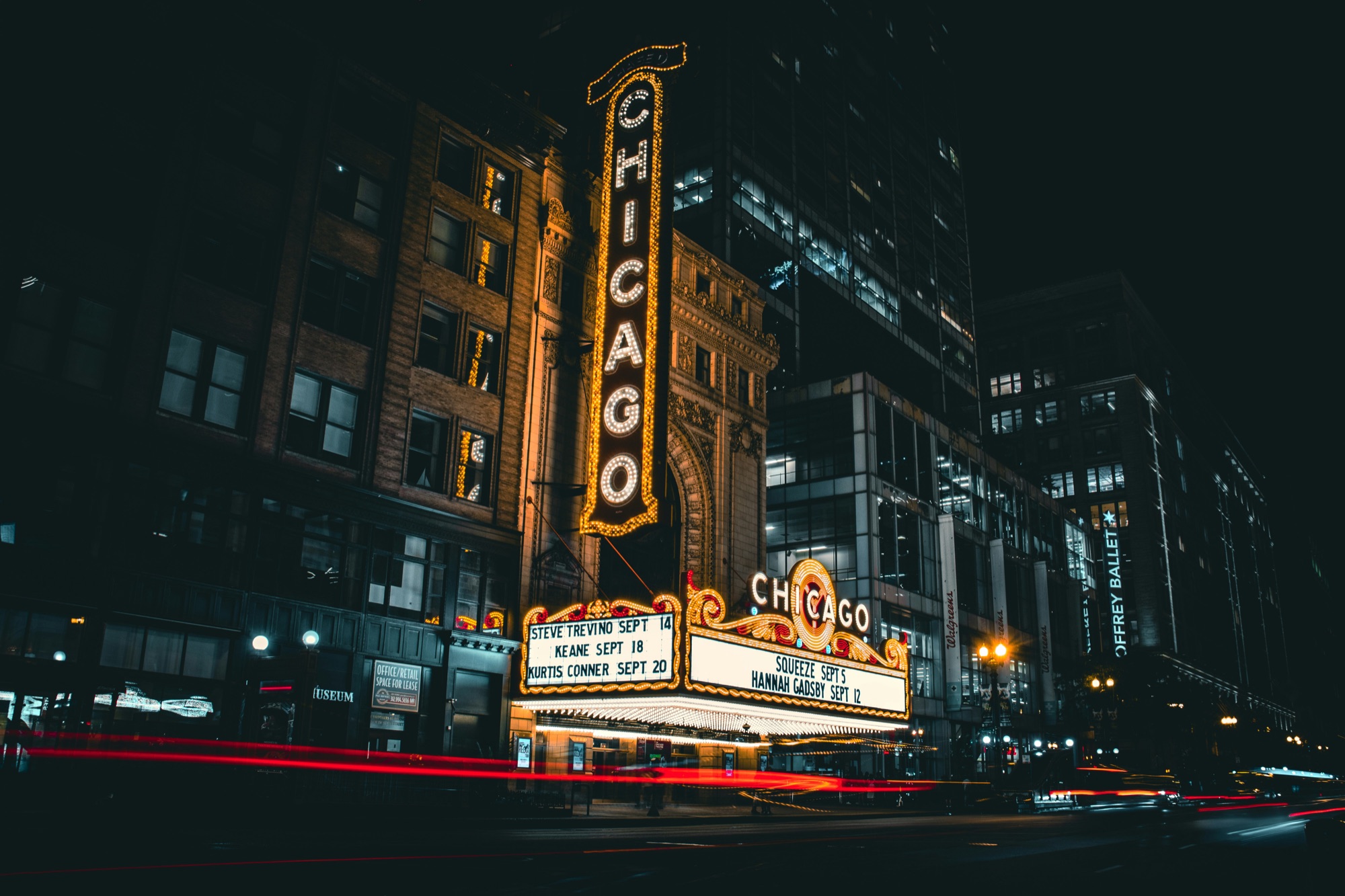 The illuminated Chicago Theatre sign above a city street with red traffic light trails