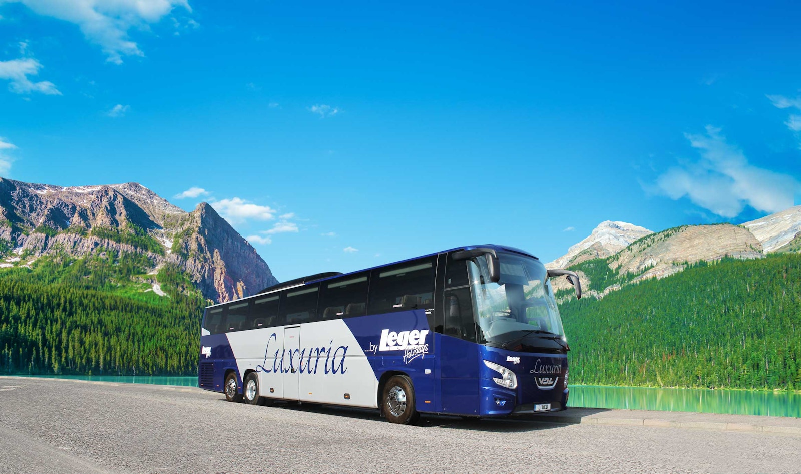 A blue and silver Leger Holidays Luxuria coach beside a mountain lake