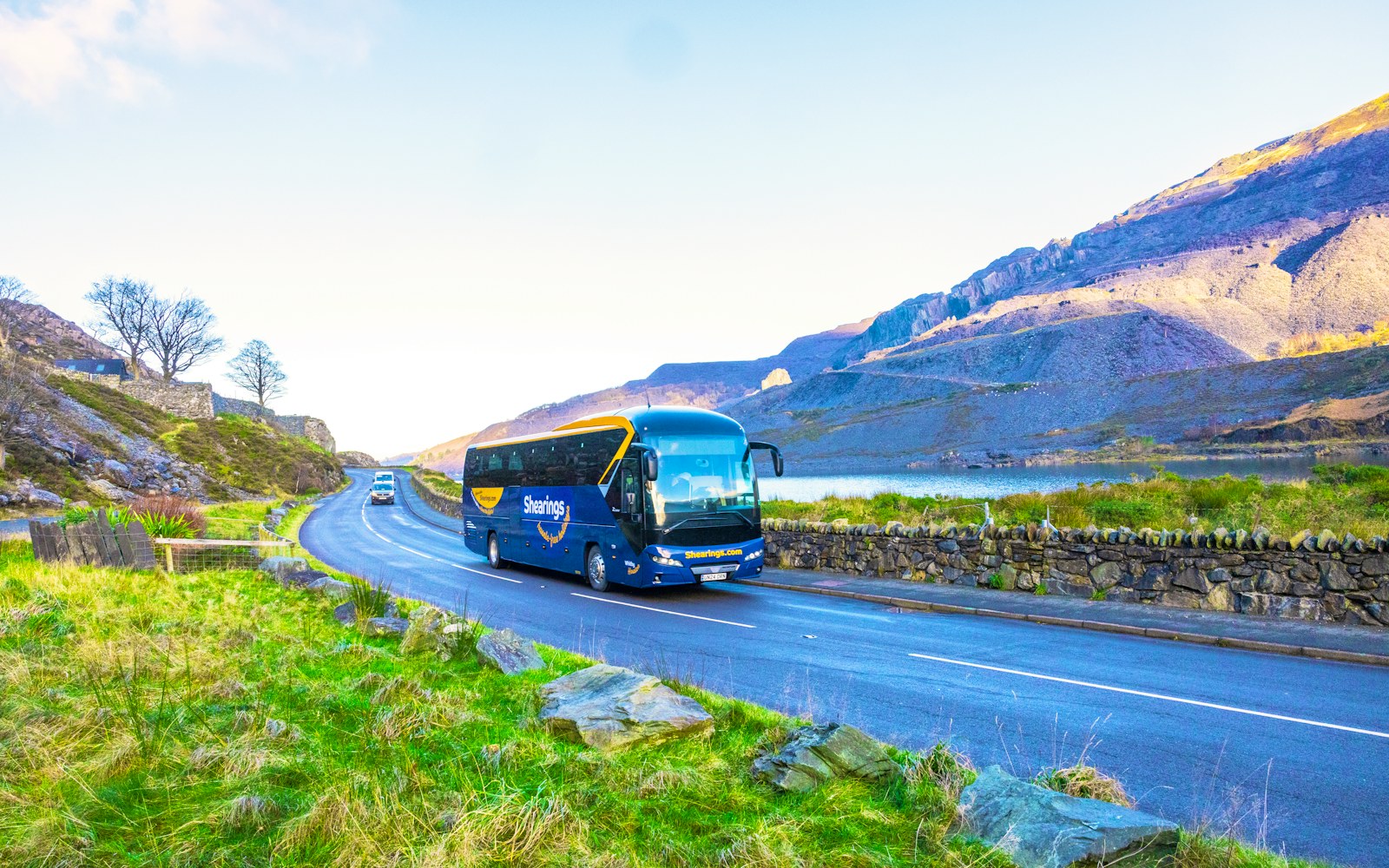 A blue Shearings coach travelling through the Welsh mountains