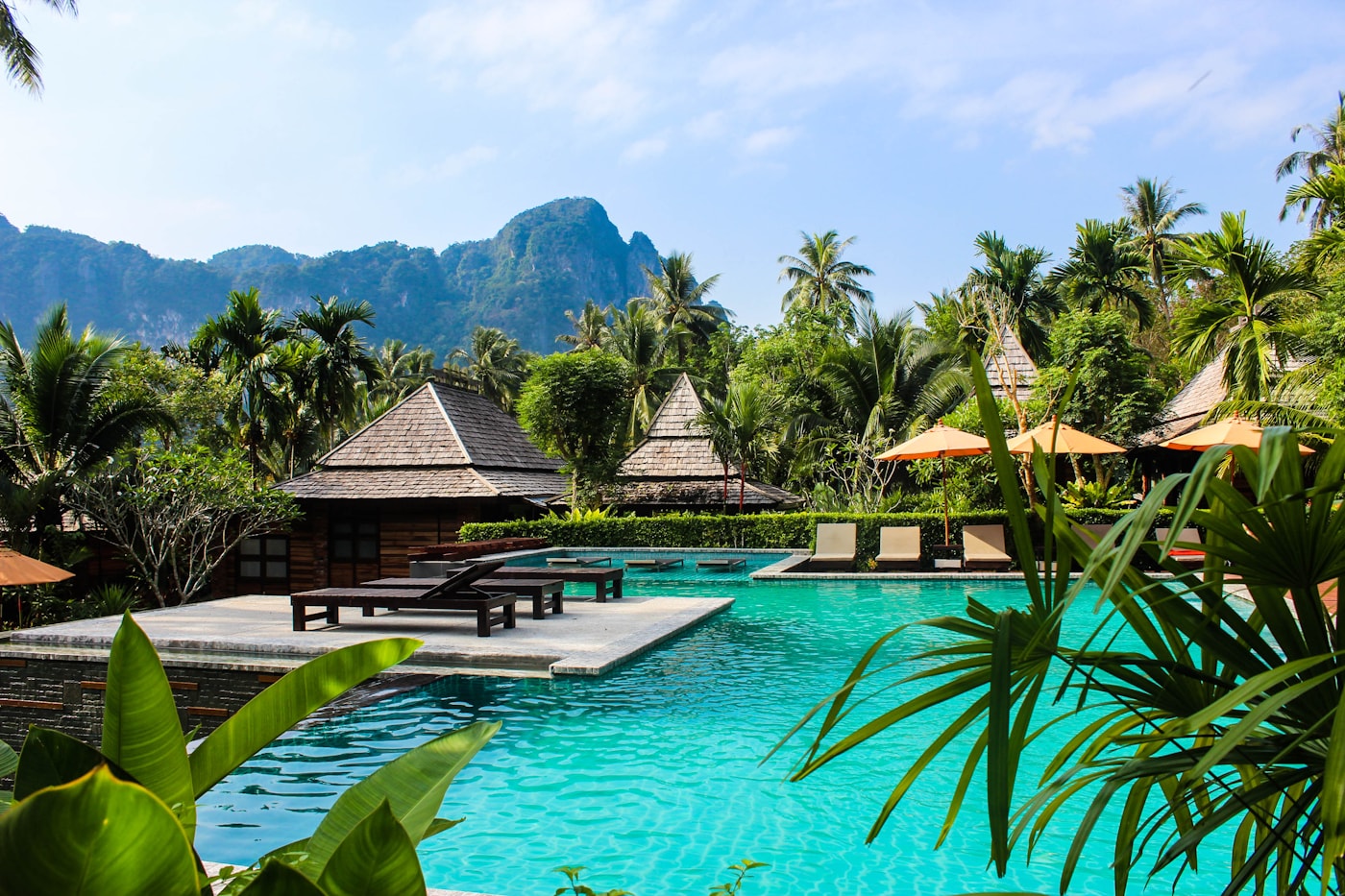 Tropical holiday resort pool surrounded by palms and mountains