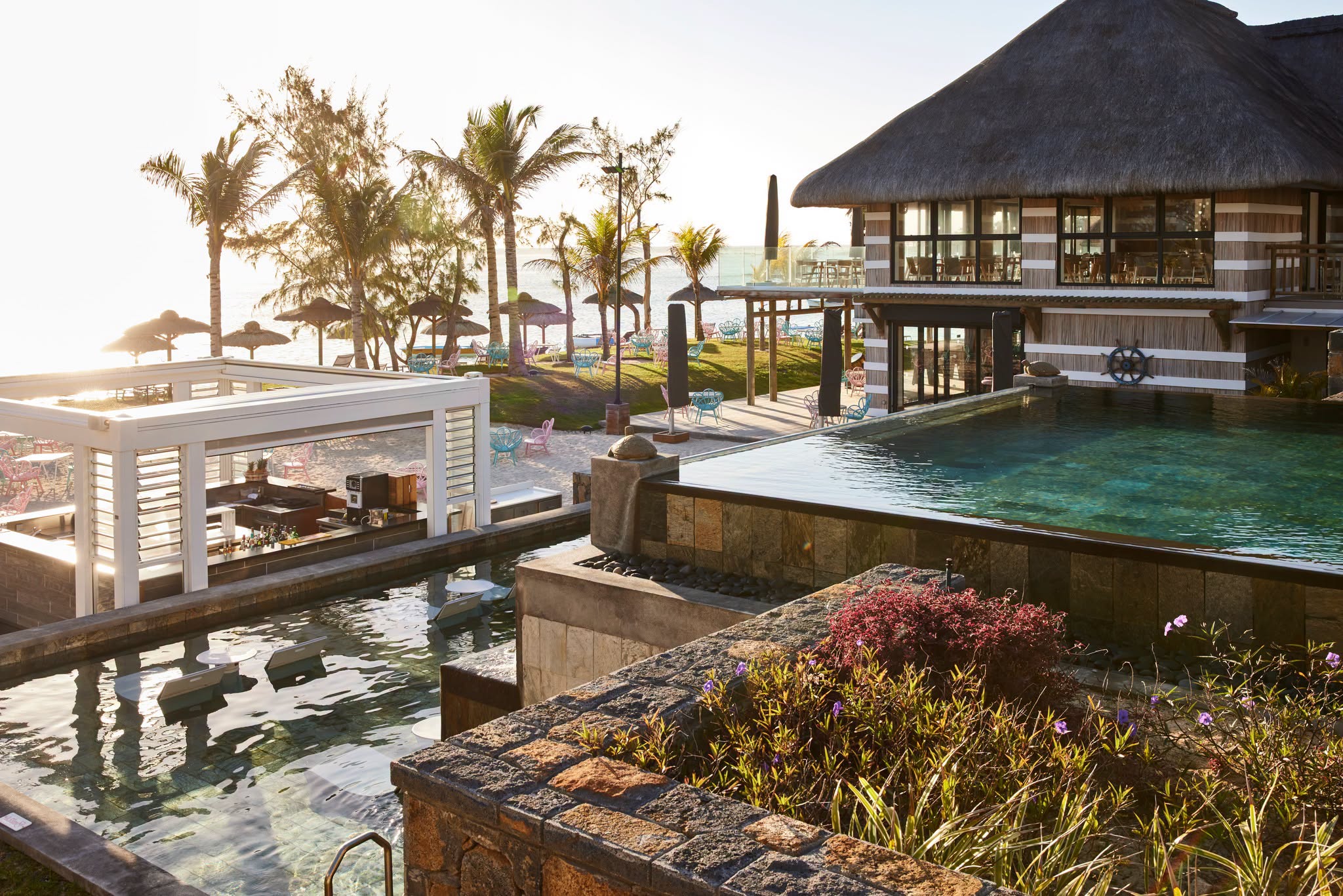 Pool, palms and beach at C Mauritius in the evening light