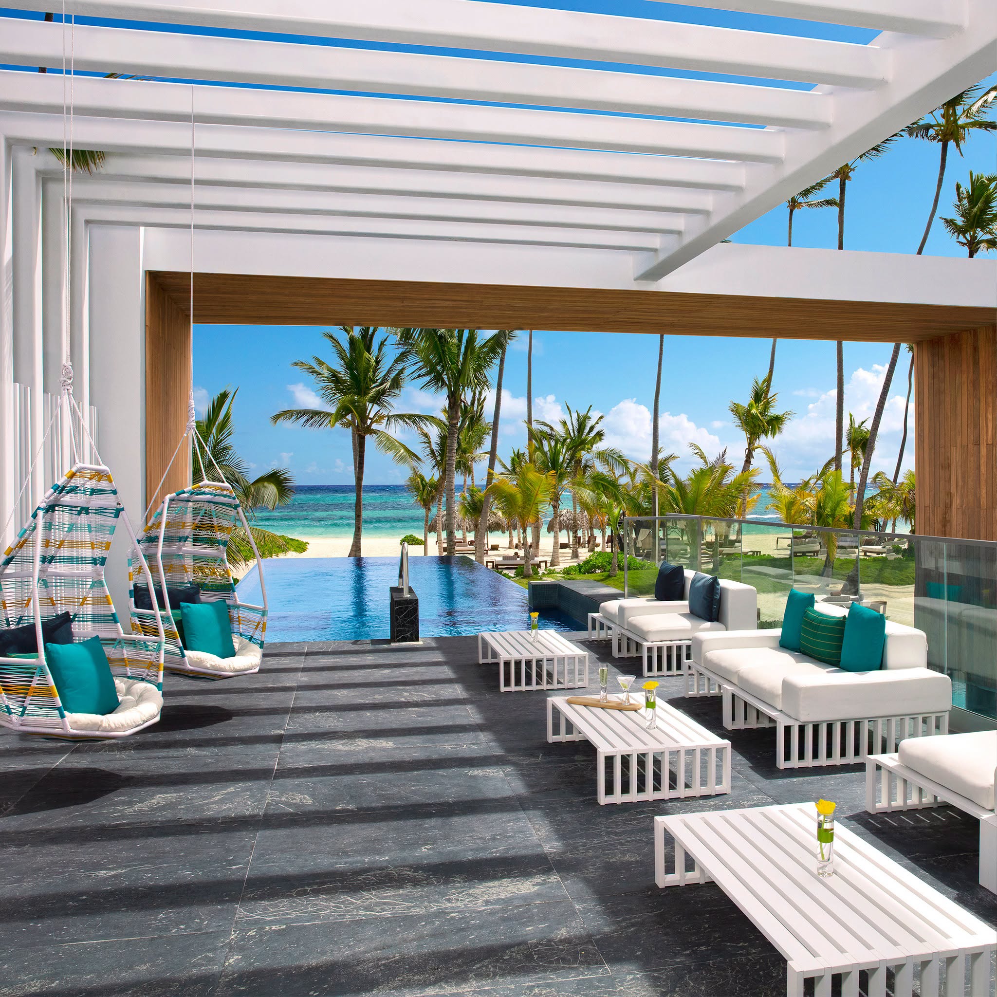 Open-air terrace overlooking a pool, palms and the sea at Secrets Royal Beach Punta Cana