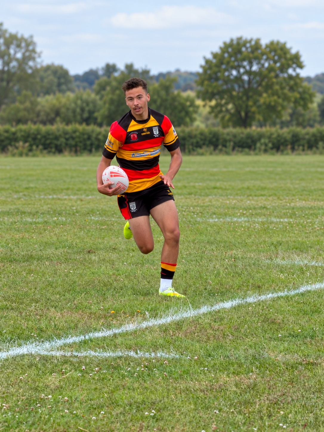 Rugby player carrying the ball, with an edited pitch background
